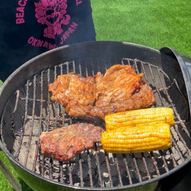 Meat and corn cooking on a barbecue grill in the garden at Villa Hale Noa