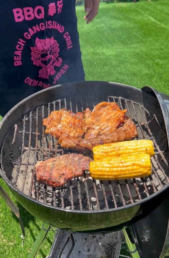 Meat and corn cooking on a barbecue grill in the garden at Villa Hale Noa