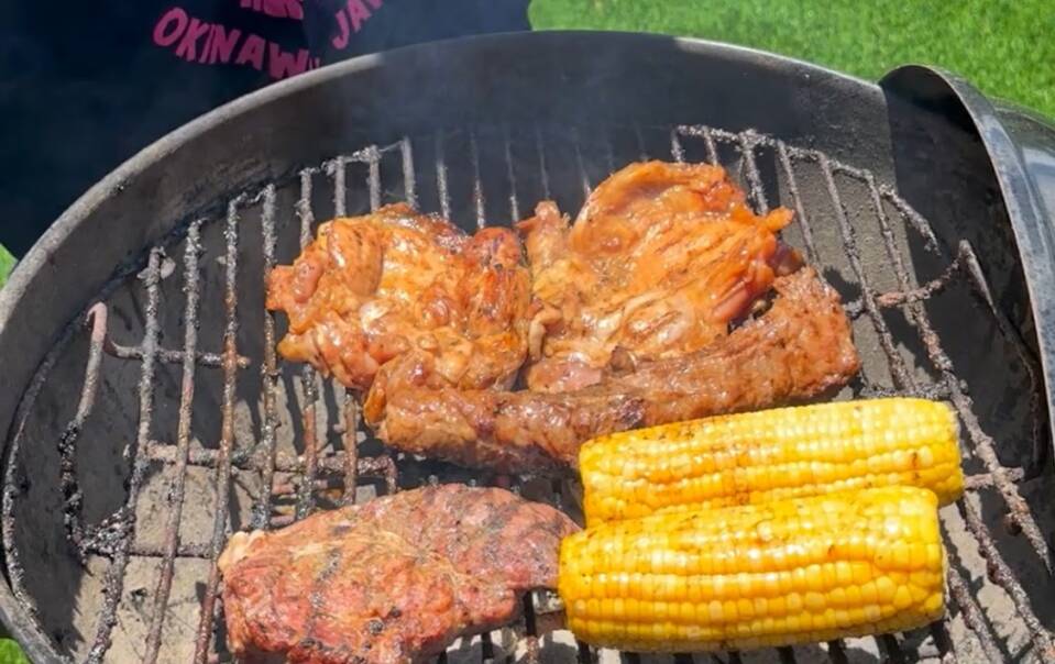 Meat and corn cooking on a barbecue grill in the garden at Villa Hale Noa